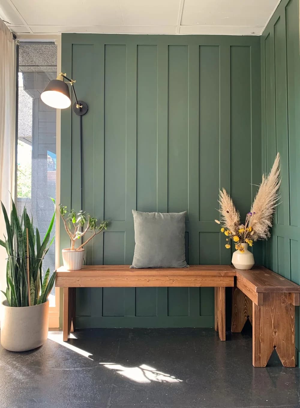 A green counselling office waiting area with a wooden bench and plants